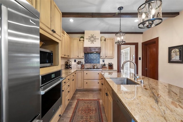 kitchen featuring stainless steel appliances, a sink, a chandelier, cream cabinetry, and light brown cabinetry