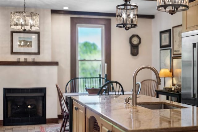 kitchen with a chandelier, a center island with sink, a sink, light stone counters, and recessed lighting