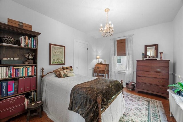 bedroom with a chandelier and wood finished floors