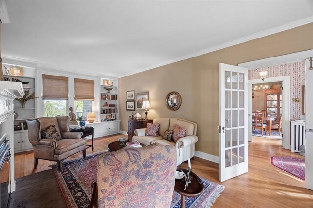living room featuring wood finished floors, ornamental molding, baseboards, french doors, and built in shelves