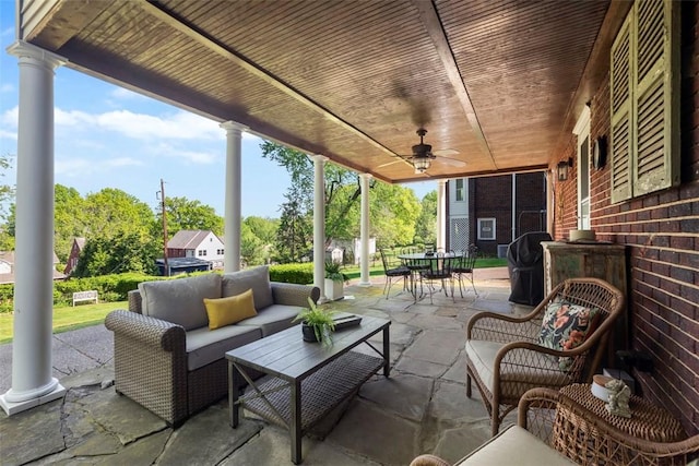 view of patio with outdoor dining space, an outdoor living space, ceiling fan, and view of wooded area