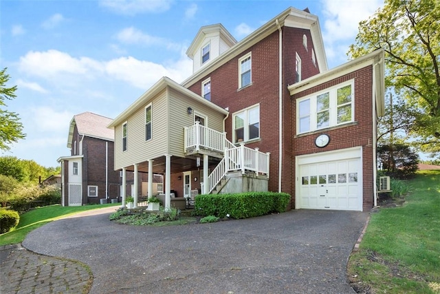 view of side of property featuring driveway, an attached garage, brick siding, stairs, and a yard