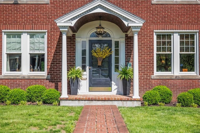 doorway to property with brick siding and a lawn