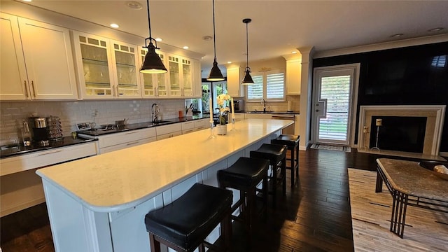 kitchen with dark wood finished floors, white cabinetry, a breakfast bar, a kitchen island, and recessed lighting