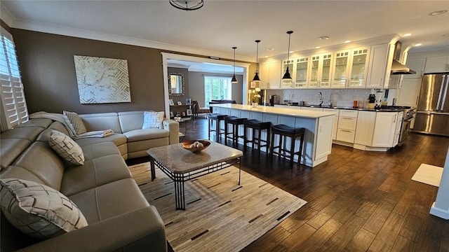 living area with dark wood-type flooring, wet bar, crown molding, and recessed lighting