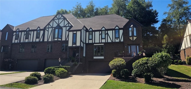 english style home with an attached garage, concrete driveway, brick siding, and stucco siding