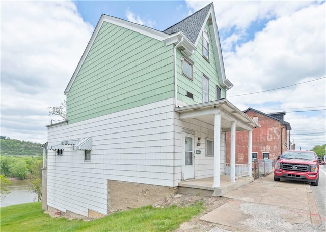 view of side of property featuring a porch and concrete driveway