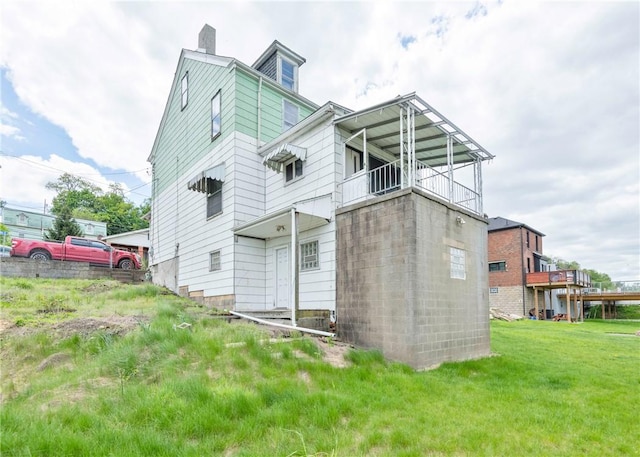 rear view of house with a chimney, a balcony, and a yard