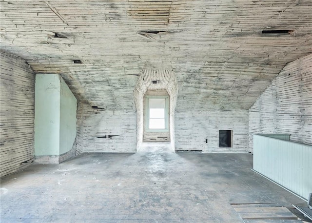 unfurnished living room with unfinished concrete flooring and vaulted ceiling