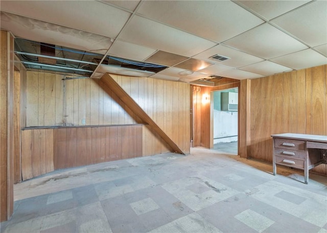 finished basement featuring wood walls, tile patterned floors, and a paneled ceiling