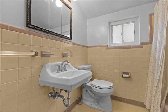 677 Olive St, Mccandless, PA 15237 - bathroom with tile walls, toilet, a shower with shower curtain, a wainscoted wall, and a sink