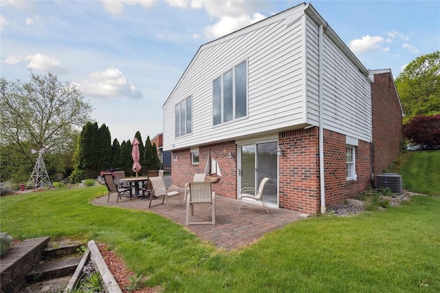 back of house featuring a patio area, central air condition unit, brick siding, and a yard