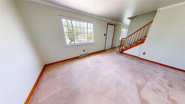 unfurnished living room with baseboards, ornamental molding, stairway, and carpet