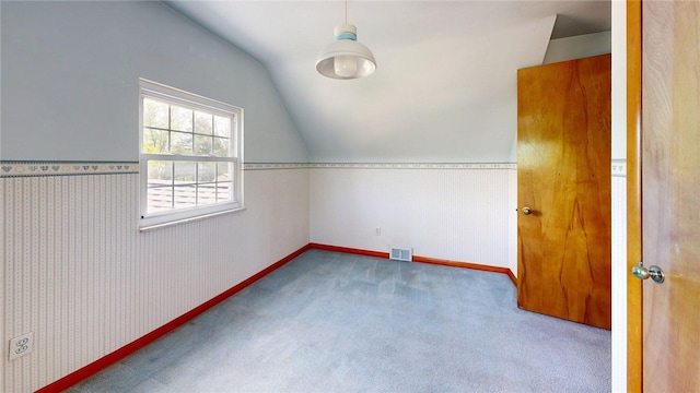 empty room featuring vaulted ceiling, carpet flooring, and baseboards