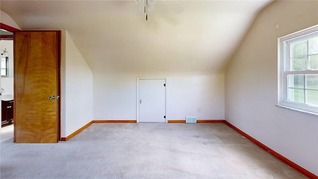 additional living space with lofted ceiling, light colored carpet, a ceiling fan, and baseboards