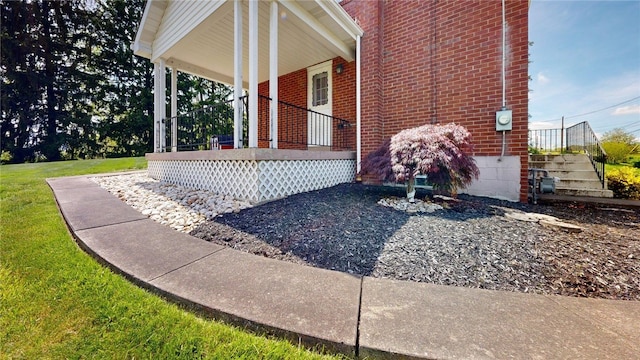 view of property exterior with covered porch, brick siding, and a yard