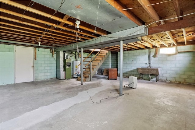 basement featuring heating unit, stairs, water heater, and a sink