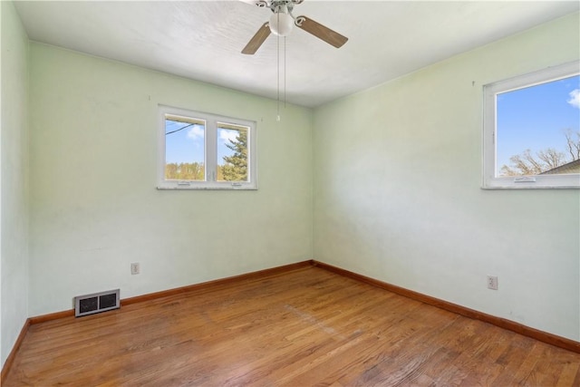 empty room featuring wood finished floors, baseboards, and a ceiling fan