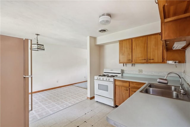 kitchen featuring white gas range, a sink, light flooring, light countertops, and brown cabinets