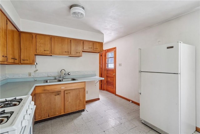 kitchen with white appliances, a sink, light countertops, brown cabinets, and baseboards