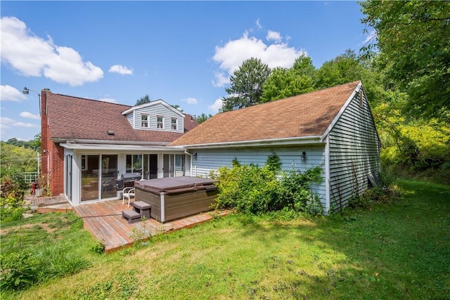 rear view of property featuring a hot tub, a wooden deck, and a yard