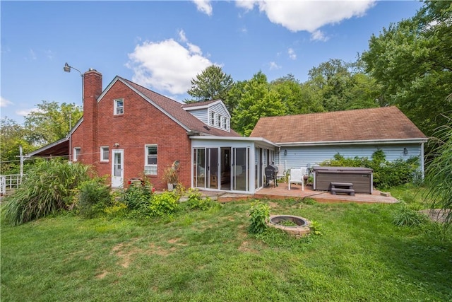 back of house featuring a hot tub, a chimney, a sunroom, and a yard