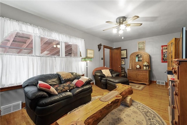 living room featuring light wood-style flooring, a ceiling fan, and baseboards