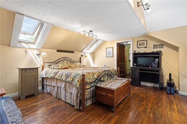 bedroom featuring a skylight, dark wood-style flooring, lofted ceiling, and baseboards