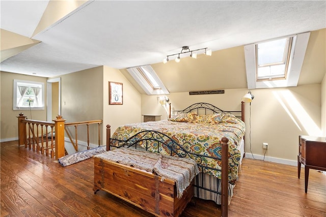 bedroom featuring a skylight, wood-type flooring, baseboards, and vaulted ceiling
