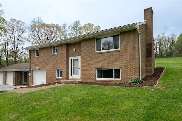 back of property featuring a chimney, brick siding, a yard, driveway, and an attached garage