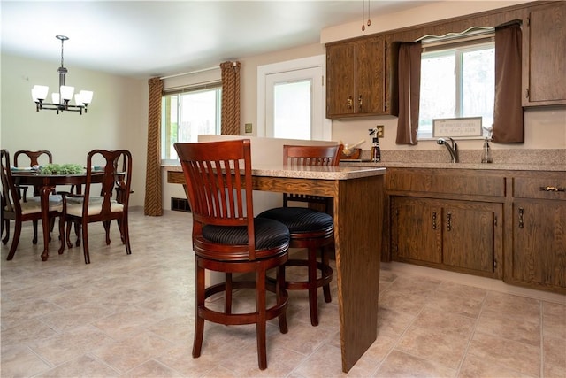 kitchen with a chandelier, a sink, healthy amount of natural light, and a breakfast bar area