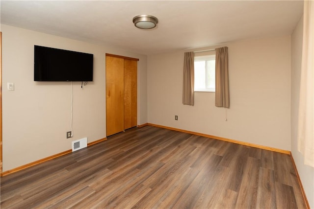 unfurnished bedroom featuring wood finished floors, baseboards, and a closet