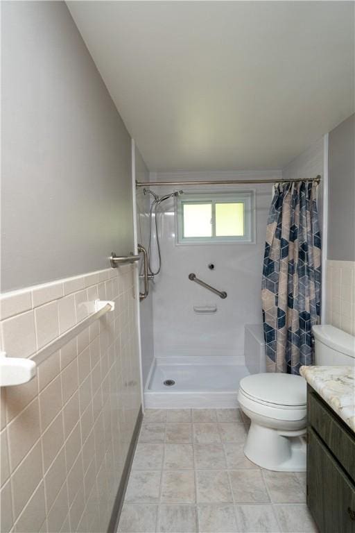 bathroom featuring tile walls, toilet, a shower with shower curtain, a wainscoted wall, and vanity