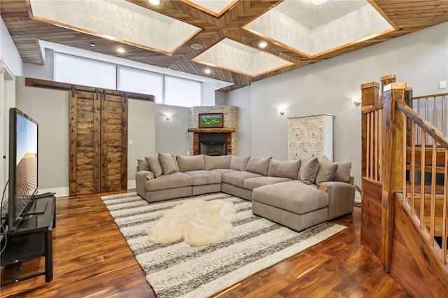 living area with dark wood-style flooring, a fireplace, stairway, a barn door, and baseboards