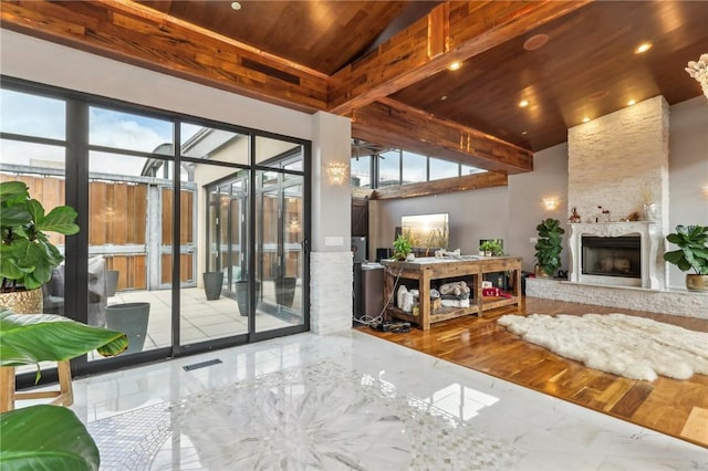 living area featuring wood ceiling, marble tiled flooring, a fireplace, and a towering ceiling