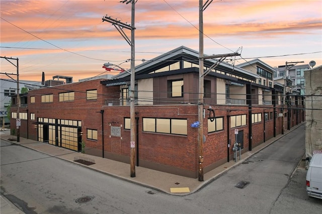 property exterior at dusk featuring brick siding
