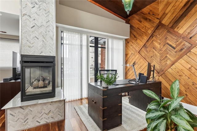 home office with a tiled fireplace, wood finished floors, and wooden walls