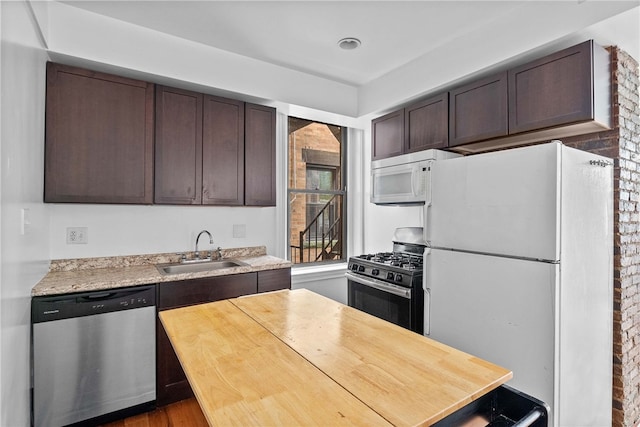 kitchen featuring stainless steel appliances, a sink, dark brown cabinetry, wooden counters, and wood finished floors