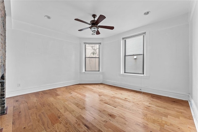 empty room featuring light wood finished floors, a ceiling fan, and baseboards