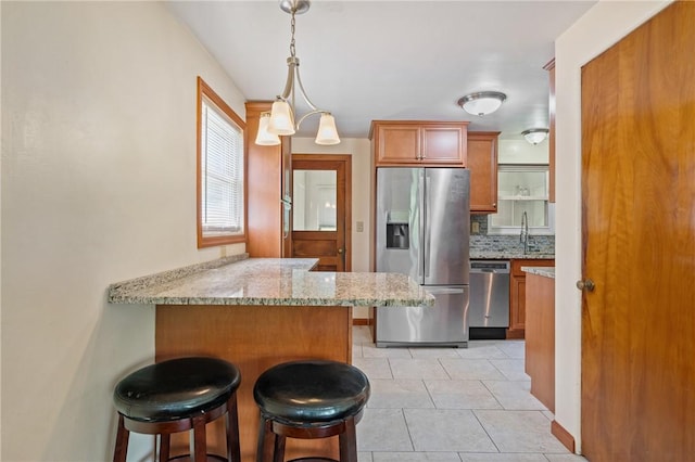 9235 Mary Ave, Mccandless, PA 15237 - kitchen featuring appliances with stainless steel finishes, light stone counters, brown cabinets, a peninsula, and a kitchen bar
