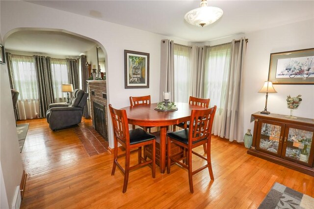 dining room with arched walkways, light wood-style floors, and healthy amount of natural light