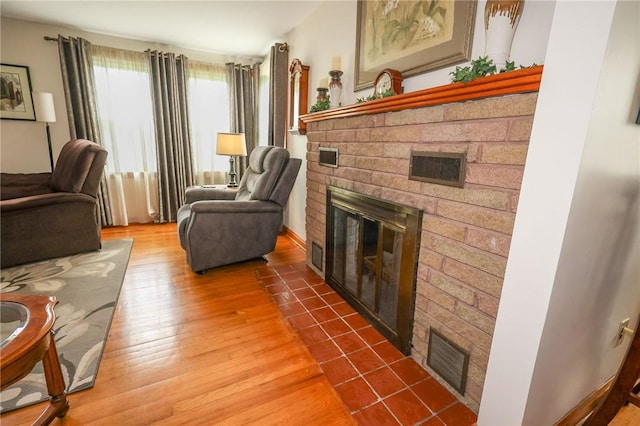 living area with a brick fireplace and wood finished floors