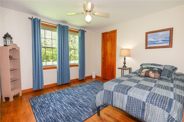bedroom with baseboards, wood finished floors, and a ceiling fan