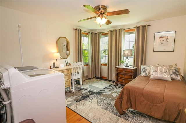 bedroom with separate washer and dryer, light wood finished floors, and ceiling fan