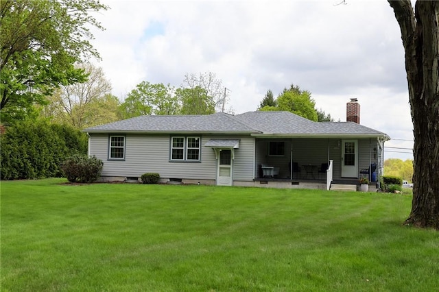 back of property with a chimney and a lawn