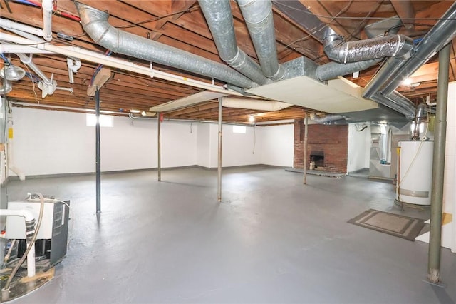 unfinished below grade area featuring water heater, a brick fireplace, and baseboards
