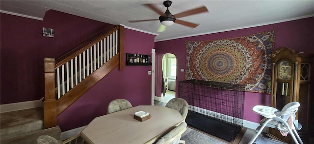 dining space with ceiling fan, arched walkways, crown molding, and stairs