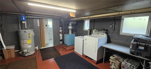 washroom featuring water heater, washer and clothes dryer, and healthy amount of natural light
