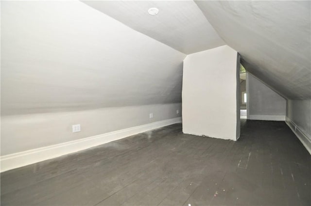 additional living space with dark wood-style flooring, lofted ceiling, and baseboards