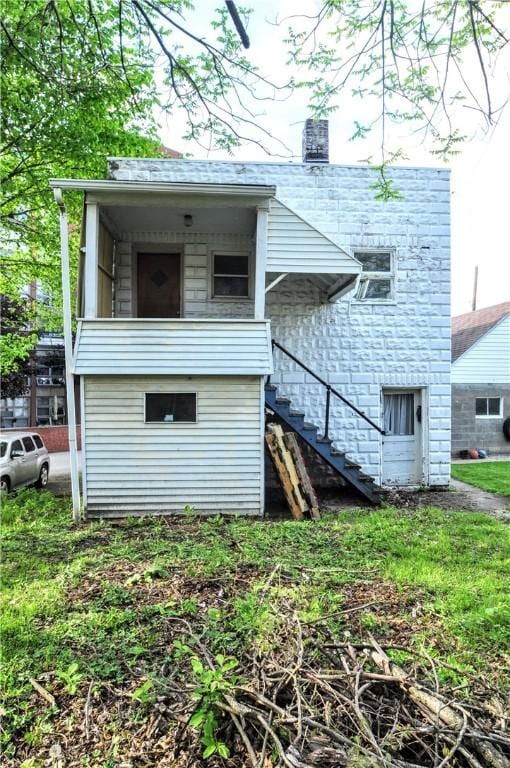 back of house featuring stairway and a chimney
